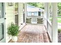 Cozy front porch with brick flooring, a hanging swing, and comfortable decorative pillows at 611 Heathermoor Ct, Charlotte, NC 28209