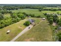 Scenic aerial view of a brick home on lush acreage, complemented by a lengthy gravel driveway and verdant trees at 6218 Indian Trail Fairview Rd, Indian Trail, NC 28079