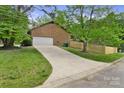 Long driveway leading to a two-car garage, surrounded by a well-maintained lawn and partial fencing at 7221 Leaves Ln, Charlotte, NC 28213