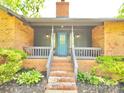Inviting front porch with brick steps and a blue door, framed by lush landscaping and gray accents at 7221 Leaves Ln, Charlotte, NC 28213