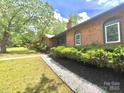 Brick home with manicured lawn, fresh mulch and stone edging, and lush trees in the yard at 7221 Leaves Ln, Charlotte, NC 28213