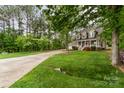Inviting two-story home with a charming front porch, lush lawn, and mature trees at 7525 Windy Pine Cir, Denver, NC 28037