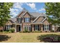 Stunning two-story brick home with lush green lawn, black shutters, and mature trees framing the facade at 10202 Alouette Dr, Waxhaw, NC 28173