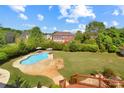 Aerial view of a backyard with a pool, patio area, lush landscaping, and green lawn at 11917 Chevis Ct, Charlotte, NC 28277