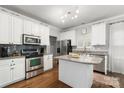 Bright kitchen featuring stainless steel appliances, an island with granite countertops, and white cabinets at 12328 Chickasaw Dr, Huntersville, NC 28078