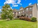 Elegant two-story home with a stone facade, lush landscaping, and a well-maintained front lawn at 15702 Guthrie Dr, Huntersville, NC 28078