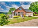 Brick home featuring an attached garage, charming awnings, and well-manicured landscaping at 181 Edgewater Rd, Hickory, NC 28601