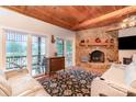 Cozy living room with stone fireplace, wood-beamed ceilings, waterfront views, and plush white sofas at 182 Meek Rd, Gastonia, NC 28056
