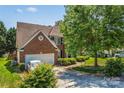 Charming brick home showcasing mature trees, a well-manicured lawn, and an attached two-car garage at 3124 Arklow Rd, Charlotte, NC 28269