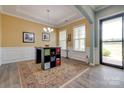 Dining room with decorative wainscoting, light hardwood flooring, recessed ceiling with chandelier, and sliding door access at 4211 Maggie Springs Way, Clover, SC 29710