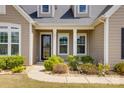 Inviting covered porch with decorative stone, elegant columns, lush landscaping, and house number above front door at 4211 Maggie Springs Way, Clover, SC 29710