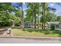 Single-story home with gray siding and black shutters surrounded by mature trees and a green lawn at 6412 Old Meadow Rd # 69, Charlotte, NC 28227