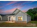 Angled view of a charming one-story home with gray siding, brick accents, and a cozy front porch at 1619 Martin Ave, Gastonia, NC 28052