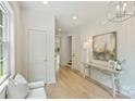 Bright hallway features light wood floors, white walls, modern lighting, and a glimpse of the staircase and outdoors beyond at 205 Coxe Ave, Charlotte, NC 28208