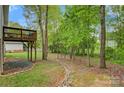 Backyard featuring mature trees, a stone pathway, and a view of the wooden deck at 2835 24Th Street Ne Dr, Hickory, NC 28601