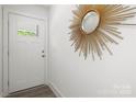 Bright entryway features white door with window and a gold sunburst mirror on white walls at 3205 Morning Dr, Charlotte, NC 28208