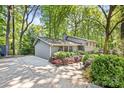 View of the home with grey siding, mature trees, and a large concrete driveway at 3329 Winnipeg Cir, Charlotte, NC 28210