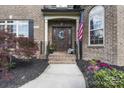 Inviting front entrance with a classic wood door, brick facade, manicured landscaping, and an American flag at 3398 Millstone Creek Rd, Lancaster, SC 29720
