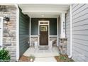 Inviting front porch with stone pillars, a stylish front door, and decorative lanterns at 4248 Black Ct # 232, Harrisburg, NC 28075