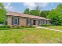 Charming brick home featuring a well-manicured lawn, classic shutters, and lush surrounding trees at 5522 Sharon Rd, Charlotte, NC 28210