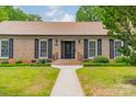 Charming brick home with a black front door, tidy landscaping, and traditional architectural details at 5522 Sharon Rd, Charlotte, NC 28210