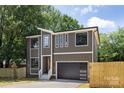 Two-story home featuring a modern design, large windows, stylish wood door, and an attached garage at 816 Tennyson Dr, Charlotte, NC 28208