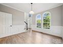 Open-concept living room with hardwood floors, wainscoting, and a large window overlooking the front yard at 817 Quince Ct, Indian Trail, NC 28079