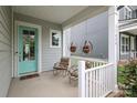 Inviting covered porch with rocking chairs, hanging floral baskets, and a turquoise front door at 13624 Jacks Ln, Pineville, NC 28134