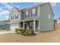 Beautiful two-story green home featuring a covered porch and manicured landscaping at 6070 Trinity Crossing Cir, Kannapolis, NC 28081