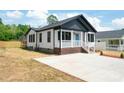 Quaint cottage with white siding, black trim, a small front porch, and manicured landscaping at 640 Central Nw Dr, Concord, NC 28027