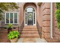 Elegant brick entryway with a welcoming arched doorway and decorative potted plants at 8905 Landsdowne Ave, Harrisburg, NC 28075