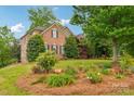 Expansive front lawn featuring beautiful flower beds and mature trees enhancing the curb appeal at 8905 Landsdowne Ave, Harrisburg, NC 28075