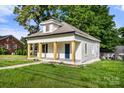 Side view of a charming white bungalow with a covered front porch, blue door, and well-kept lawn at 906 Church St, Kings Mountain, NC 28086