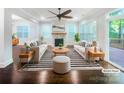 Bright, staged living room with fireplace, ceiling fan, and hardwood floors, complemented by natural light from large windows at 911 Balsam Ter, Charlotte, NC 28214