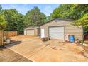 View of two spacious metal garages with concrete driveway and wooded area at 1005 Caldon Dr, Stanley, NC 28164