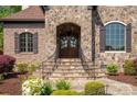 Stunning stone entrance with a detailed dark wood door and intricate iron railings, inviting you home at 1304 Lookout Cir, Waxhaw, NC 28173