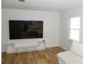 Bright living room featuring modern laminate flooring, a TV, white walls, and a white sofa at 149 Glenwood Dr, Rock Hill, SC 29732