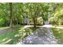 Well-maintained single-story home with a detached garage and a long driveway surrounded by trees at 16320 Peach Grove Ln, Charlotte, NC 28277