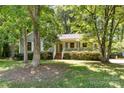 Charming single-story home with a cozy front porch surrounded by lush greenery and mature trees at 16320 Peach Grove Ln, Charlotte, NC 28277