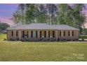 Charming single-story brick home featuring arched entryway, manicured lawn and mature trees at 205 Timberfield Trl, China Grove, NC 28023