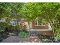 A classic brick home features a cozy front porch with iron railings and manicured landscaping at 2125 Chatham Ave, Charlotte, NC 28205