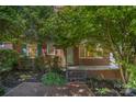 A charming brick home features a cozy front porch with iron railings and beautiful landscaping at 2125 Chatham Ave, Charlotte, NC 28205