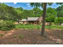 View of a well-maintained brick home with a large front yard and mature trees surrounding the property at 2202 Bearskin Ln, Monroe, NC 28110