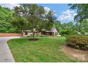 Brick home featuring a circular driveway, manicured lawn, mature tree, and welcoming front porch at 2202 Bearskin Ln, Monroe, NC 28110