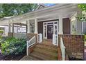 Inviting front porch with brick steps, white railings, and covered seating area at 2311 Club Rd, Charlotte, NC 28205