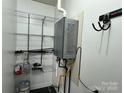 Utility room features a tankless water heater, shelving, and tool hooks for efficient organization and convenience at 396 Pitts School Nw Rd, Concord, NC 28027