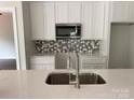 A modern kitchen with white cabinets, stainless steel appliances, a tiled backsplash, and a quartz countertop at 418 W Westview St, Gastonia, NC 28052