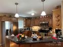 Well-lit kitchen with stainless steel appliances, wood cabinets, and stone countertops at 506 E Pine St, Maiden, NC 28650
