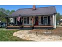 Inviting home with a covered front porch, rocking chairs, and a red front door at 548 Alspaugh Dam Rd, Taylorsville, NC 28681