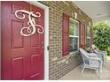 Inviting front porch with brick columns, decorative door wreath, and white wicker seating for relaxing at 6041 Laurent Ave, Fort Mill, SC 29715